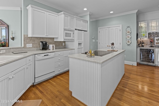 kitchen with backsplash, white appliances, light hardwood / wood-style flooring, beverage cooler, and a center island