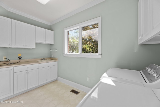 laundry room featuring washing machine and clothes dryer, sink, crown molding, and cabinets