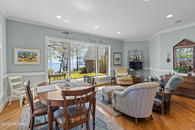 dining space with ornamental molding and light hardwood / wood-style flooring