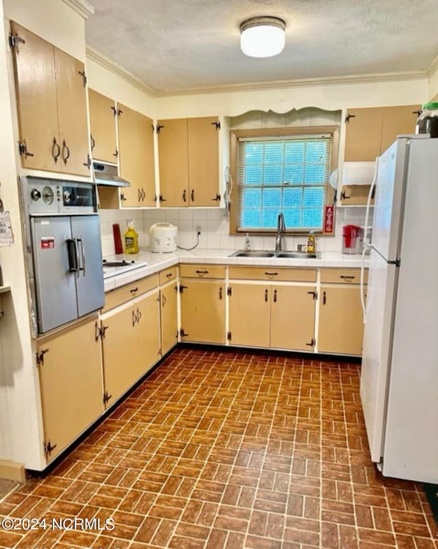 kitchen featuring white refrigerator, a textured ceiling, tasteful backsplash, ornamental molding, and sink