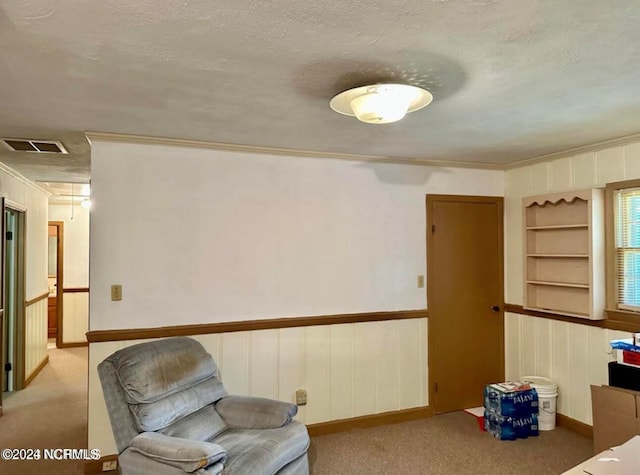 living area with built in features, a textured ceiling, and light colored carpet