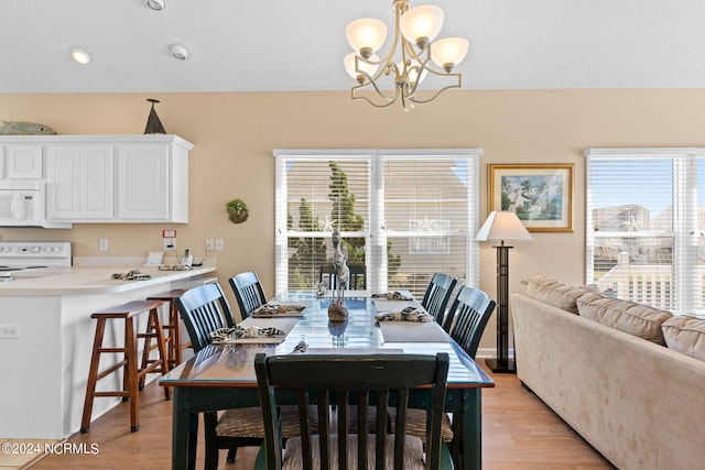 dining area featuring light wood-type flooring, plenty of natural light, and an inviting chandelier