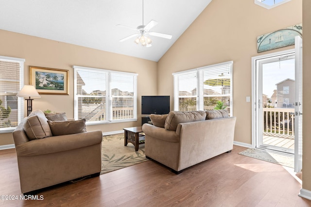 living area featuring high vaulted ceiling, ceiling fan, baseboards, and wood finished floors