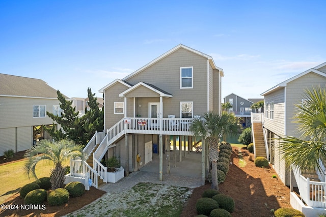 beach home featuring a carport, a porch, stairway, and driveway