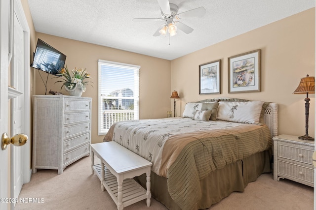 bedroom featuring light carpet, ceiling fan, and a textured ceiling