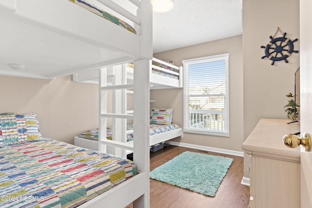 bedroom with visible vents, a textured ceiling, baseboards, and wood finished floors