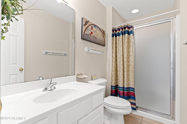 full bathroom featuring vanity, a stall shower, tile patterned flooring, and toilet