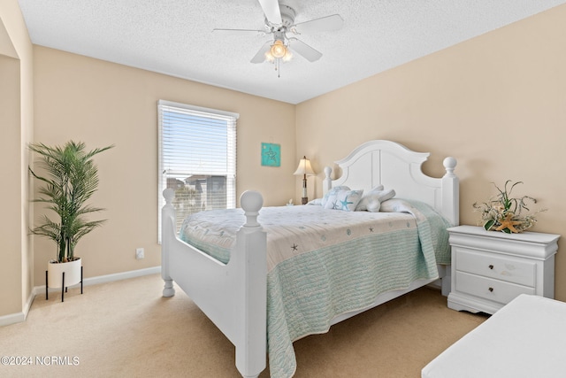 bedroom with ceiling fan, baseboards, a textured ceiling, and light colored carpet