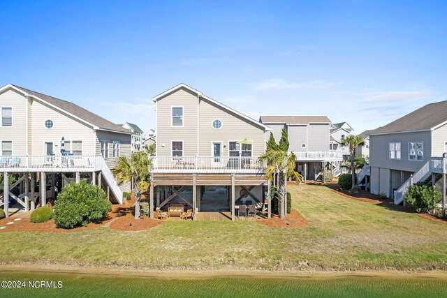 back of house featuring a lawn and a deck with water view