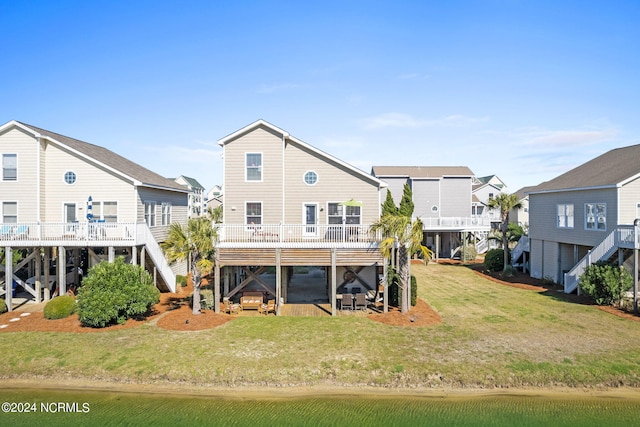 back of house featuring stairs, a residential view, a lawn, and a wooden deck