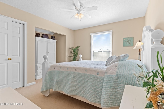 bedroom with a textured ceiling, ceiling fan, and light colored carpet