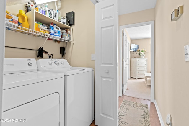 washroom with laundry area, separate washer and dryer, light wood-style floors, and baseboards