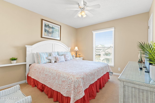 bedroom with light carpet, a textured ceiling, a ceiling fan, and baseboards