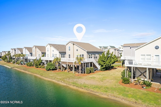 back of house with a residential view, a deck with water view, a yard, and stairs