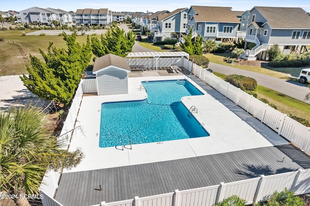 community pool with a patio area, a fenced backyard, a residential view, and a pergola