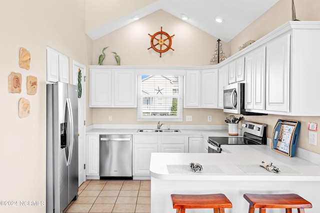 kitchen featuring light tile patterned floors, light countertops, appliances with stainless steel finishes, a sink, and a peninsula