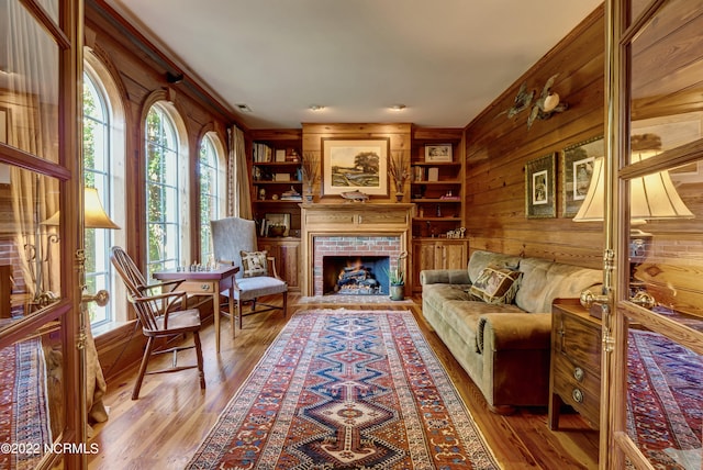 interior space with built in features, wooden walls, hardwood / wood-style flooring, and a fireplace