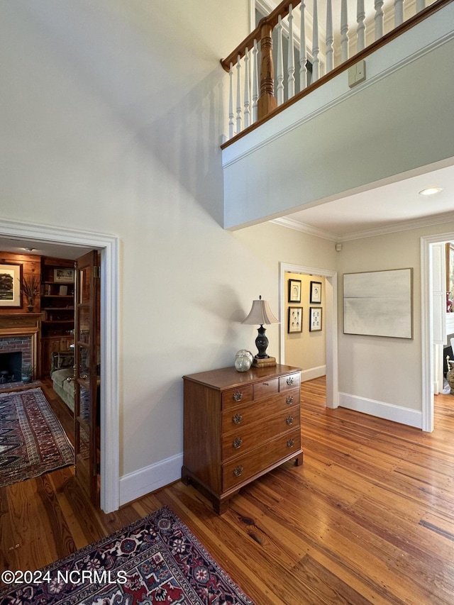 staircase with hardwood / wood-style floors, ornamental molding, and a fireplace