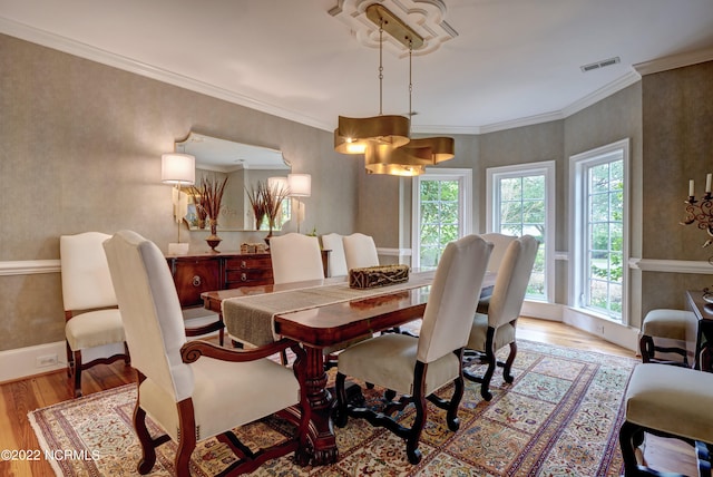 dining area with crown molding, a chandelier, and light hardwood / wood-style flooring