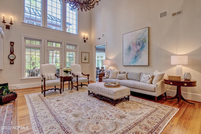 living room with a high ceiling, a chandelier, and light hardwood / wood-style floors