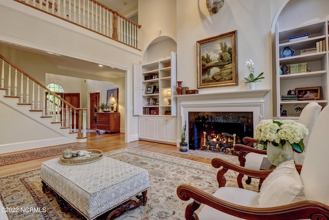 living room with built in shelves, light hardwood / wood-style floors, and a high ceiling