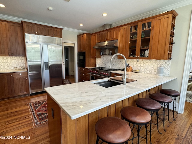 kitchen featuring backsplash, a kitchen bar, sink, stainless steel built in fridge, and dark hardwood / wood-style floors