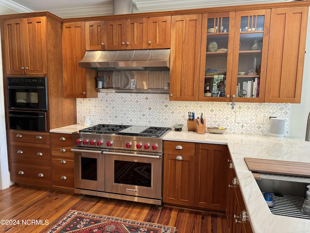 kitchen with dark hardwood / wood-style floors, tasteful backsplash, range with two ovens, and wall chimney range hood