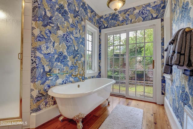 bathroom with ornamental molding, wood-type flooring, and a bathing tub