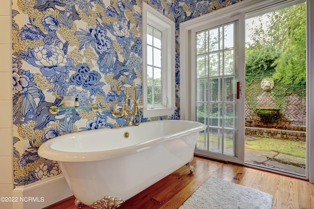 bathroom featuring a tub, wood-type flooring, and a wealth of natural light