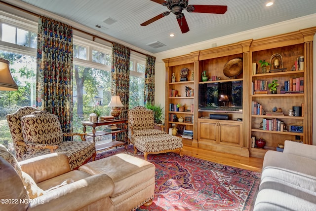 living room featuring ceiling fan, ornamental molding, and hardwood / wood-style flooring