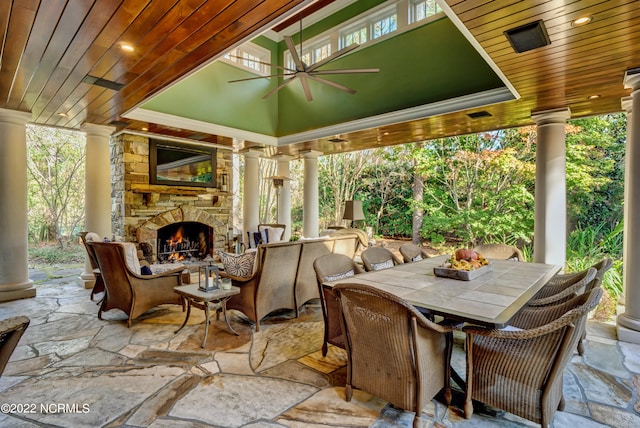 view of terrace with an outdoor stone fireplace and ceiling fan