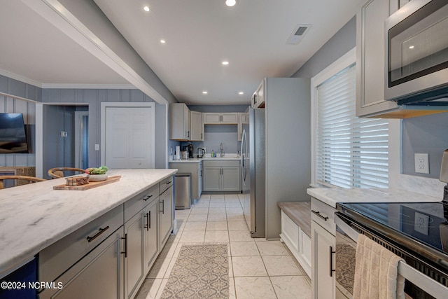 kitchen featuring ceiling fan, light tile flooring, pendant lighting, a center island, and appliances with stainless steel finishes