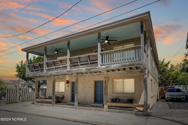 view of front of house with ceiling fan and a balcony