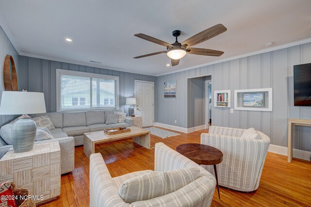 living room with light hardwood / wood-style floors, ornamental molding, and ceiling fan