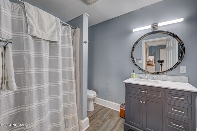 bathroom with a healthy amount of sunlight, hardwood / wood-style floors, toilet, and large vanity