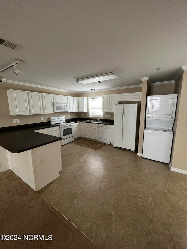 kitchen featuring stacked washer and clothes dryer, white appliances, kitchen peninsula, crown molding, and white cabinets