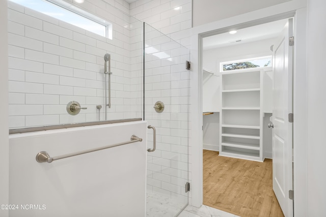 bathroom featuring a shower with door, plenty of natural light, and hardwood / wood-style floors