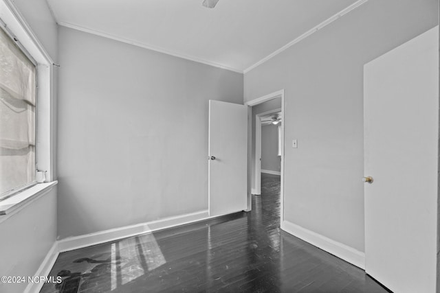 spare room featuring dark hardwood / wood-style floors, ceiling fan, a wealth of natural light, and ornamental molding