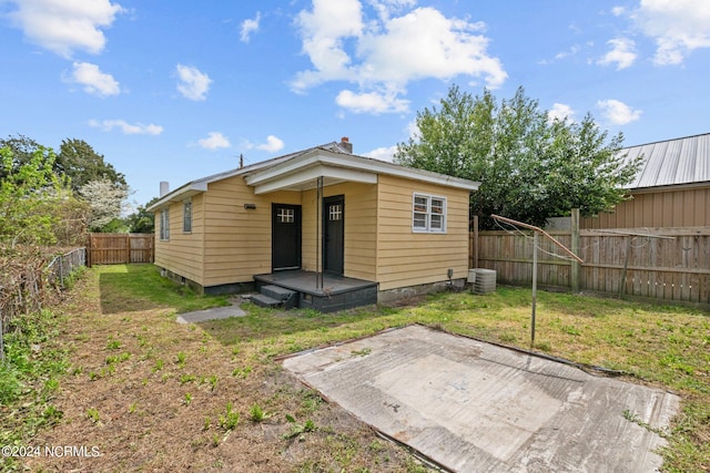 rear view of property featuring a lawn, central AC, and a patio