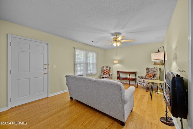 living room with a textured ceiling, light hardwood / wood-style flooring, and ceiling fan