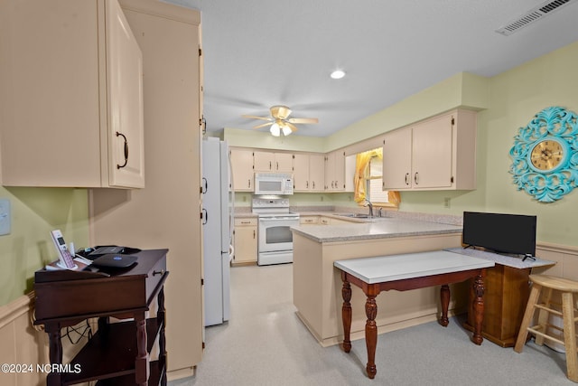 kitchen with white appliances, a kitchen bar, kitchen peninsula, sink, and ceiling fan