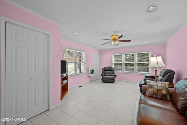 tiled living room featuring ceiling fan, ornamental molding, heating unit, and a textured ceiling