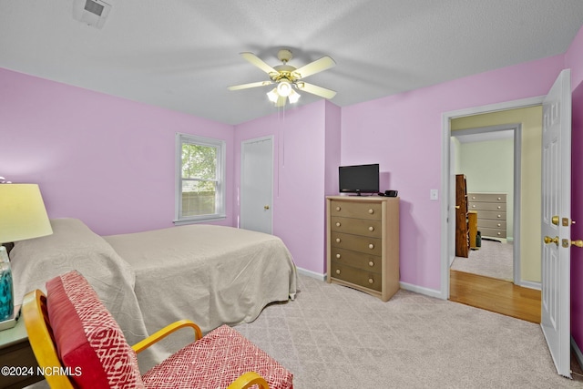 bedroom with light colored carpet, a textured ceiling, and ceiling fan