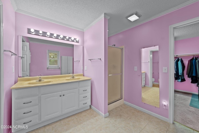 bathroom featuring a shower with door, vanity, ornamental molding, and a textured ceiling