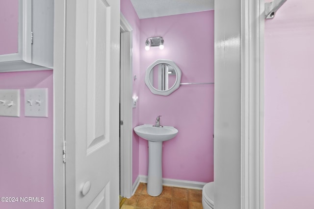 bathroom with toilet, sink, and a textured ceiling