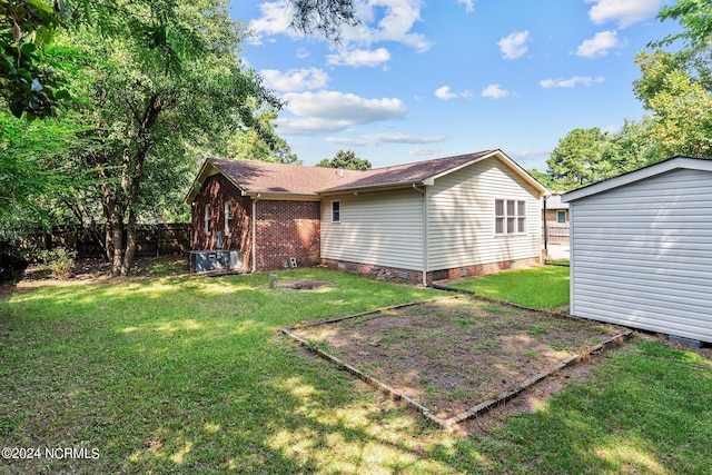 rear view of property featuring a yard and a storage shed