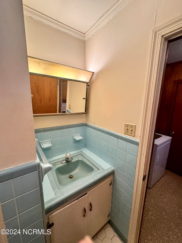 bathroom featuring tile walls, vanity with extensive cabinet space, washer / clothes dryer, tile flooring, and tasteful backsplash