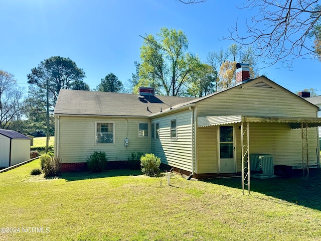 rear view of house featuring central AC, a lawn, and a storage unit