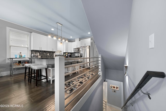 kitchen with white cabinets, pendant lighting, dark wood-type flooring, and a breakfast bar