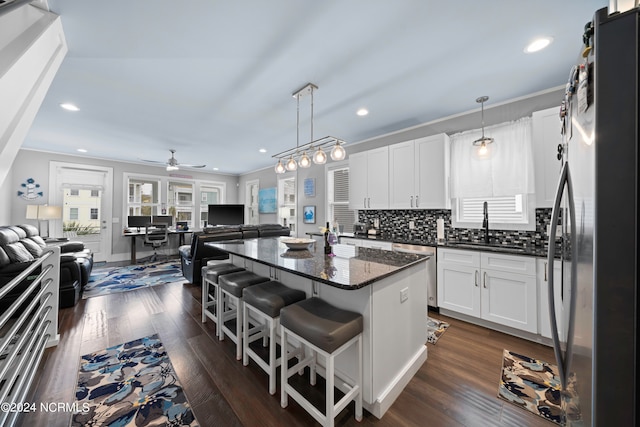 kitchen with dark wood-type flooring, a kitchen island, stainless steel appliances, pendant lighting, and ceiling fan